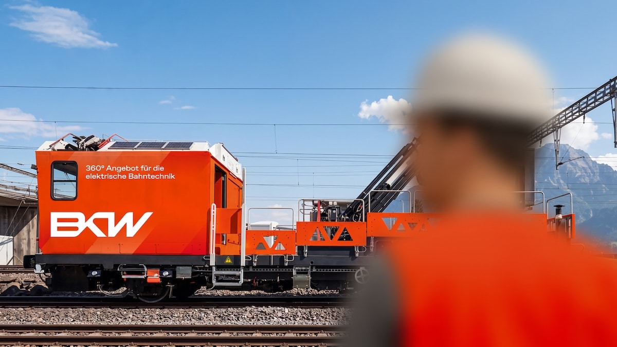 Oranges BKW Schienenfahrzeug für die elektrische Bahntechnik mit einem Mitarbeiter im Vordergrund