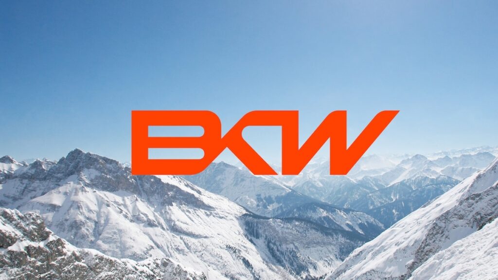 Oranges BKW Logo vor verschneiter Berglandschaft unter blauem Himmel