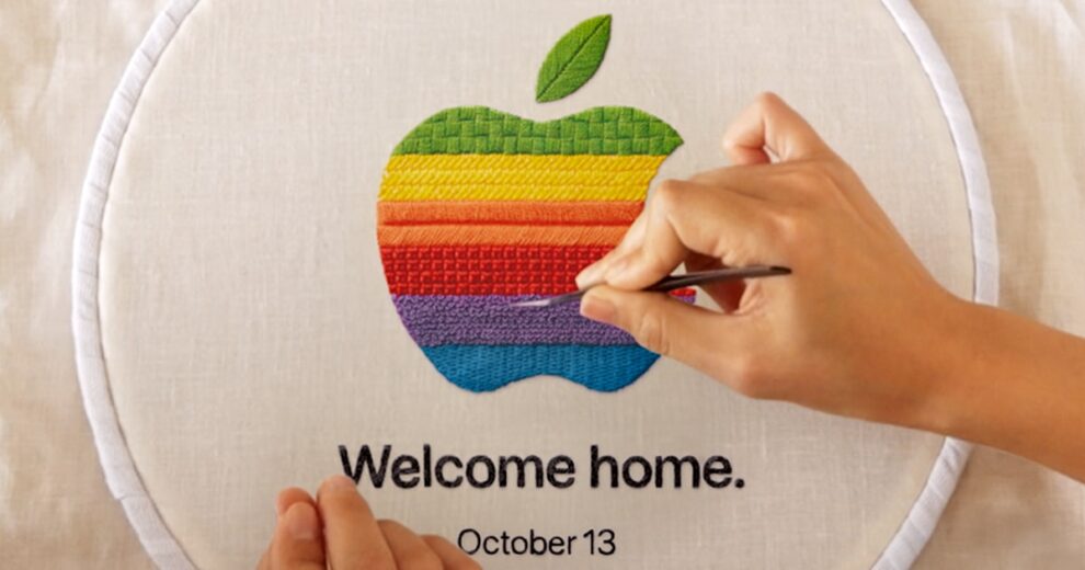 Hand mit Nadel stickt das Regenbogen-Logo von Apple auf Stoff, darunter der Schriftzug Welcome home und das Datum October 13