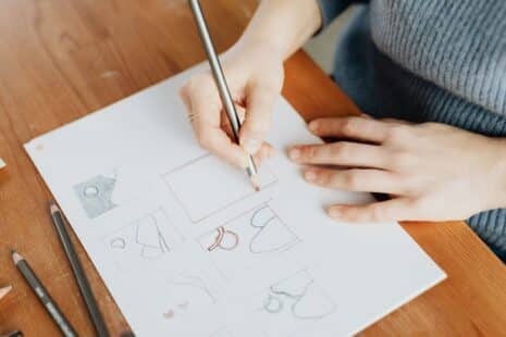 Designerin skizziert mit Bleistift mehrere Logo-Entwürfe von Hand auf Papier