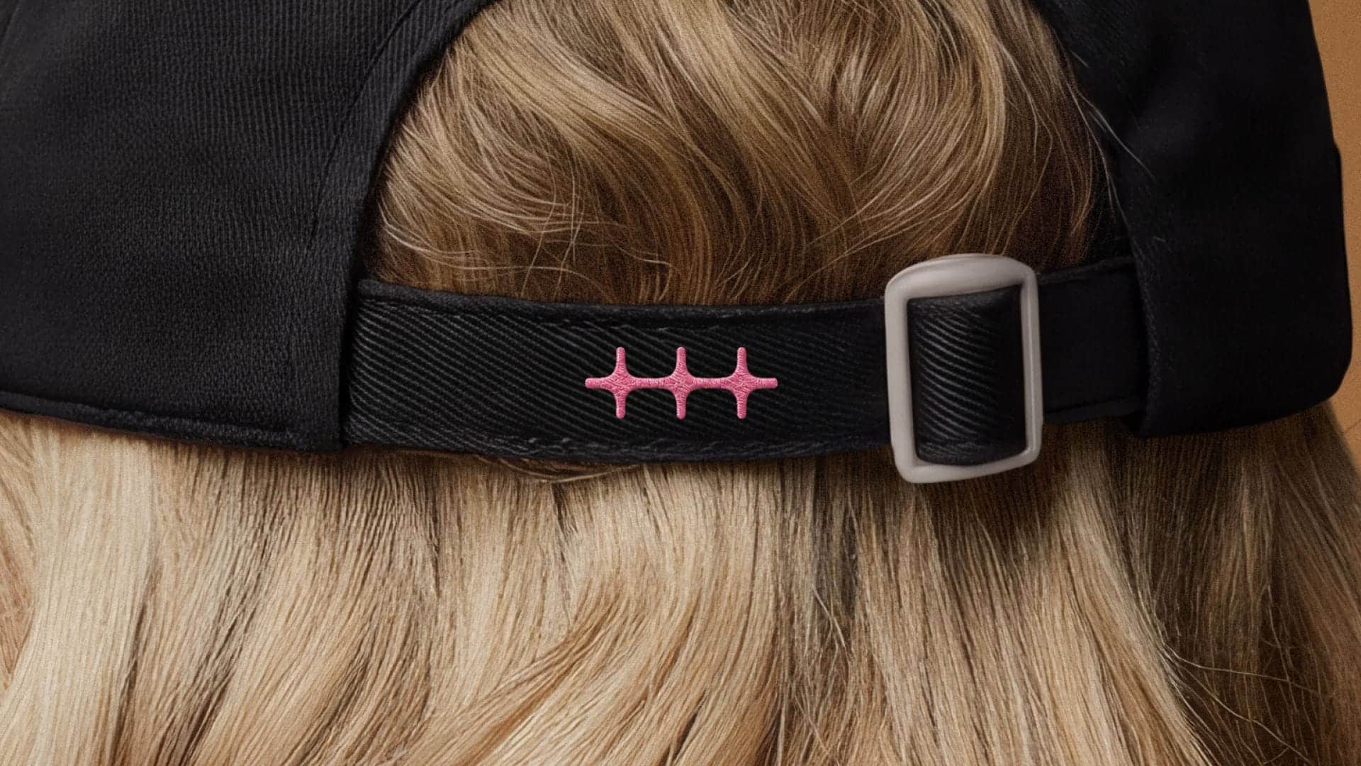 Rosa gesticktes n8n-Logo am Verschluss einer schwarzen Cap