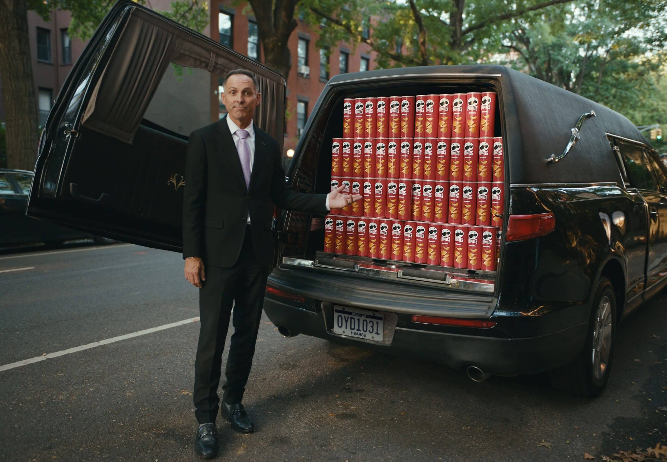 Bestatter präsentiert einen Leichenwagen, der mit Pringles-Dosen gefüllt ist
